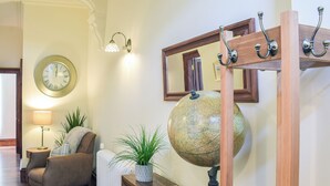 A cozy living room with a wooden floor, a round wall clock, a globe, a lamp, and a comfortable chair. - 2 bedroom accommodation in Ardrossan, near Ayr (Ardrossan, near Ayr)