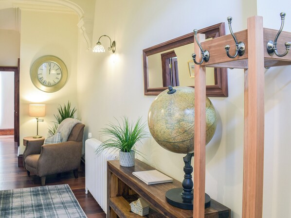 Ein gemütliches Wohnzimmer mit Holzboden, einer runden Wanduhr, einem Globus, einer Lampe und einem bequemen Sessel.