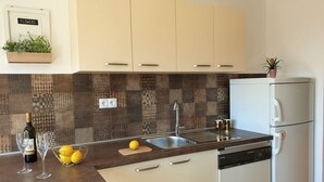 A modern kitchen with a patterned backsplash, a built-in dishwasher, and a small potted plant on the countertop. - Apartment with balcony, parking near the center and the sea (Crikvenica)