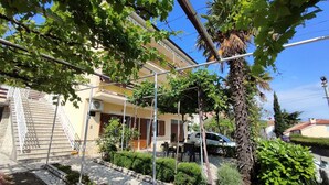 A residential building with a stone staircase, a balcony, and a car parked in front. - Apartment with balcony, parking near the center and the sea (Crikvenica)