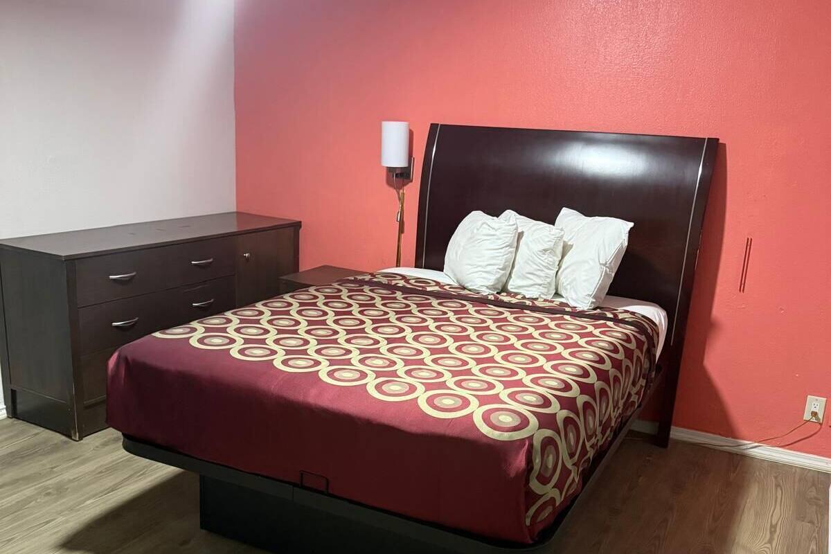 Een slaapkamer met een bed, een dressoir en een nachtkastje.