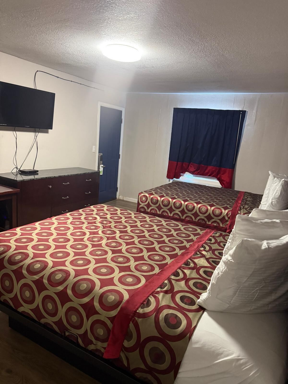 Habitación de hotel con dos camas, televisión y escritorio.