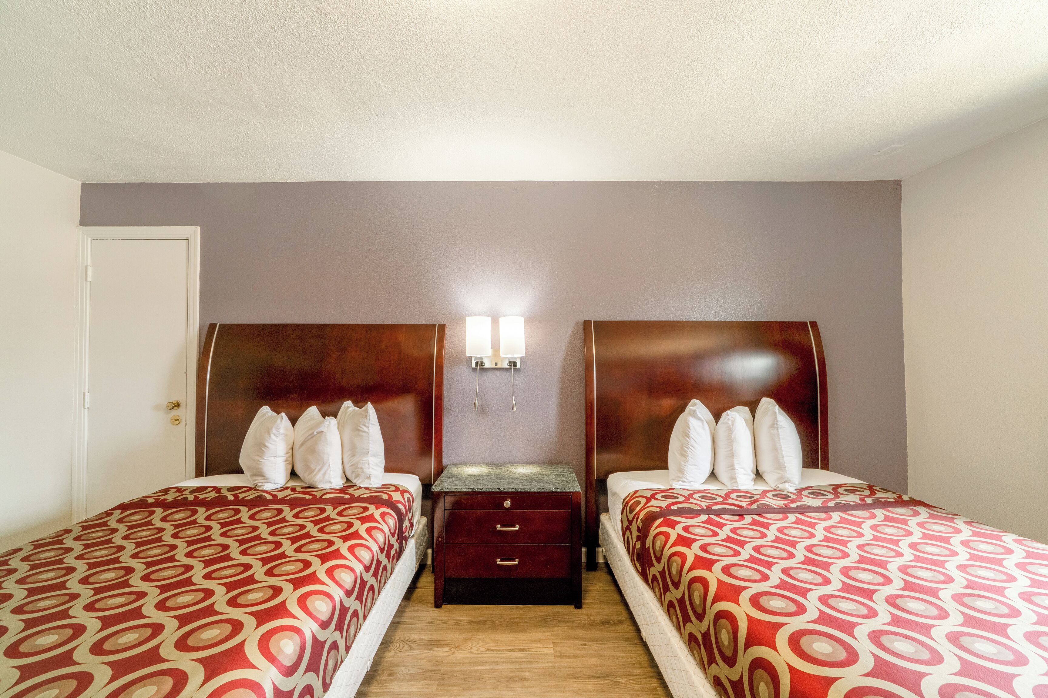 A twin room with two beds, a nightstand, and a wall-mounted light.