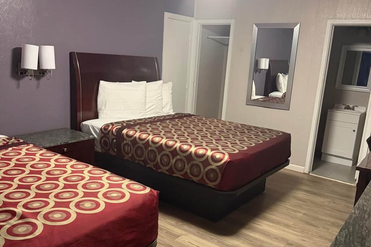 Een hotelkamer met twee bedden, een badkamer en een spiegel.