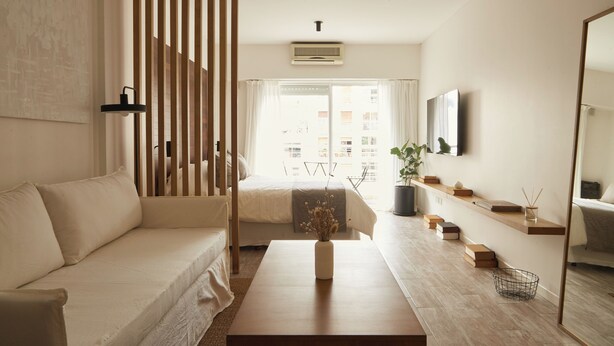 A modern, minimalist living room with a sofa, a coffee table, a TV, and a bookshelf. - Hestia at Cabrera 3200 (Buenos Aires)