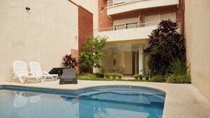 A swimming pool with lounge chairs and potted plants. - Hestia at Cabrera 3200 (Buenos Aires)