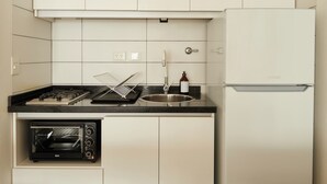 A compact kitchen with white cabinets, a built-in oven, a sink, and a refrigerator. - Hestia at Cabrera 3200 (Buenos Aires)
