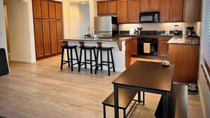 Una cucina moderna con mobili in legno, un'isola centrale con sgabelli, forno integrato e microonde.