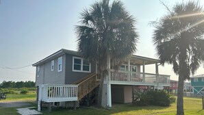 A two-story house with a wooden deck and a staircase leading to the upper level. - Beautiful Beach House In Fort Morgan !  (Gulf Shores)