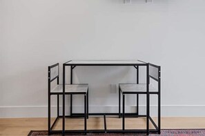 Simple, functional design with a small table and two chairs against a plain white wall.