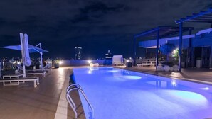Una piscina en la azotea con vistas despejadas del horizonte urbano nocturno.