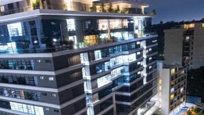 Un hotel de varios pisos con un diseño moderno, que cuenta con balcones en cada planta y una terraza en la azotea.