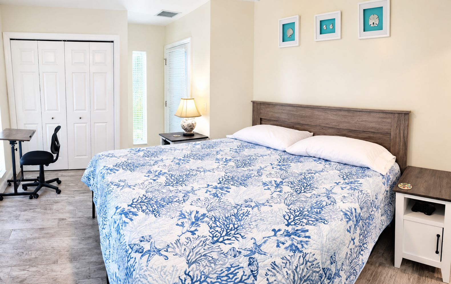 A bedroom with a bed, a desk, a chair, and a nightstand.