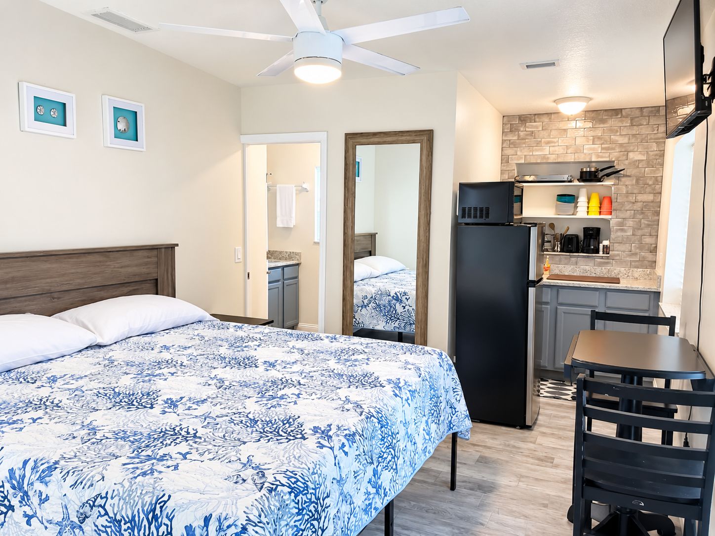 Une chambre avec un lit, un bureau et un coin cuisine.