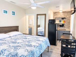 A bedroom with a bed, a desk, and a kitchenette. - Seashell Studio - Private Hot Tub, King Bed, Ocean View, Short Walk to the Beach (St. Augustine)