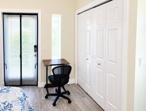 Un dormitorio con cama, escritorio, silla y armario.