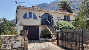 Ein zweigeschossiges Haus mit einer Steineinfahrt, einer gefliesten Terrasse und einem Tor.
