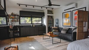 A modern kitchen with dark cabinetry, a built-in stove, and a large window. - LeSuite Santa Teresa  (Cóbano)