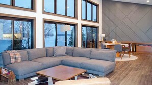 A modern living room with a sectional sofa, a coffee table, and a dining area with a table and chairs.