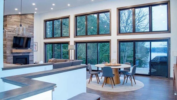 A modern kitchen with a built-in TV, a fireplace, and a large window overlooking a snowy landscape.