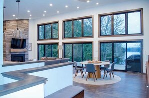 A modern kitchen with a built-in TV, a fireplace, and a large window overlooking a snowy landscape.