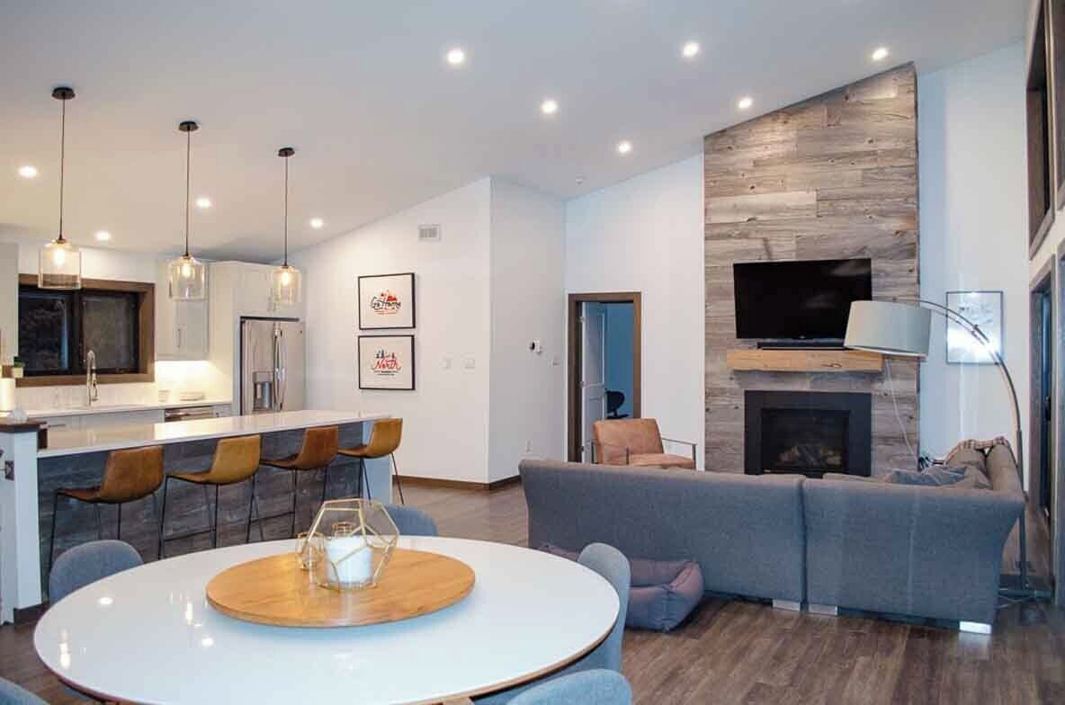 A modern living room with a grey sofa, a fireplace, and a TV mounted on the wall.