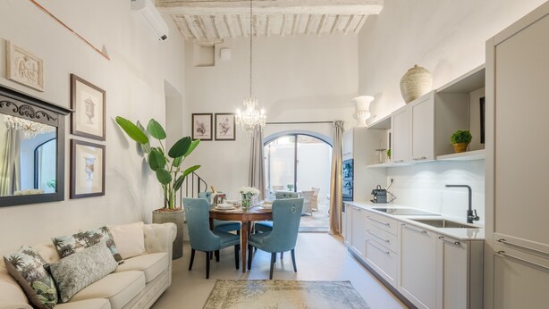 A modern kitchen with white cabinets, a dining area with a table and chairs, and a large plant. - Gallo Cedrone a Home With Outdoor (Lucca)