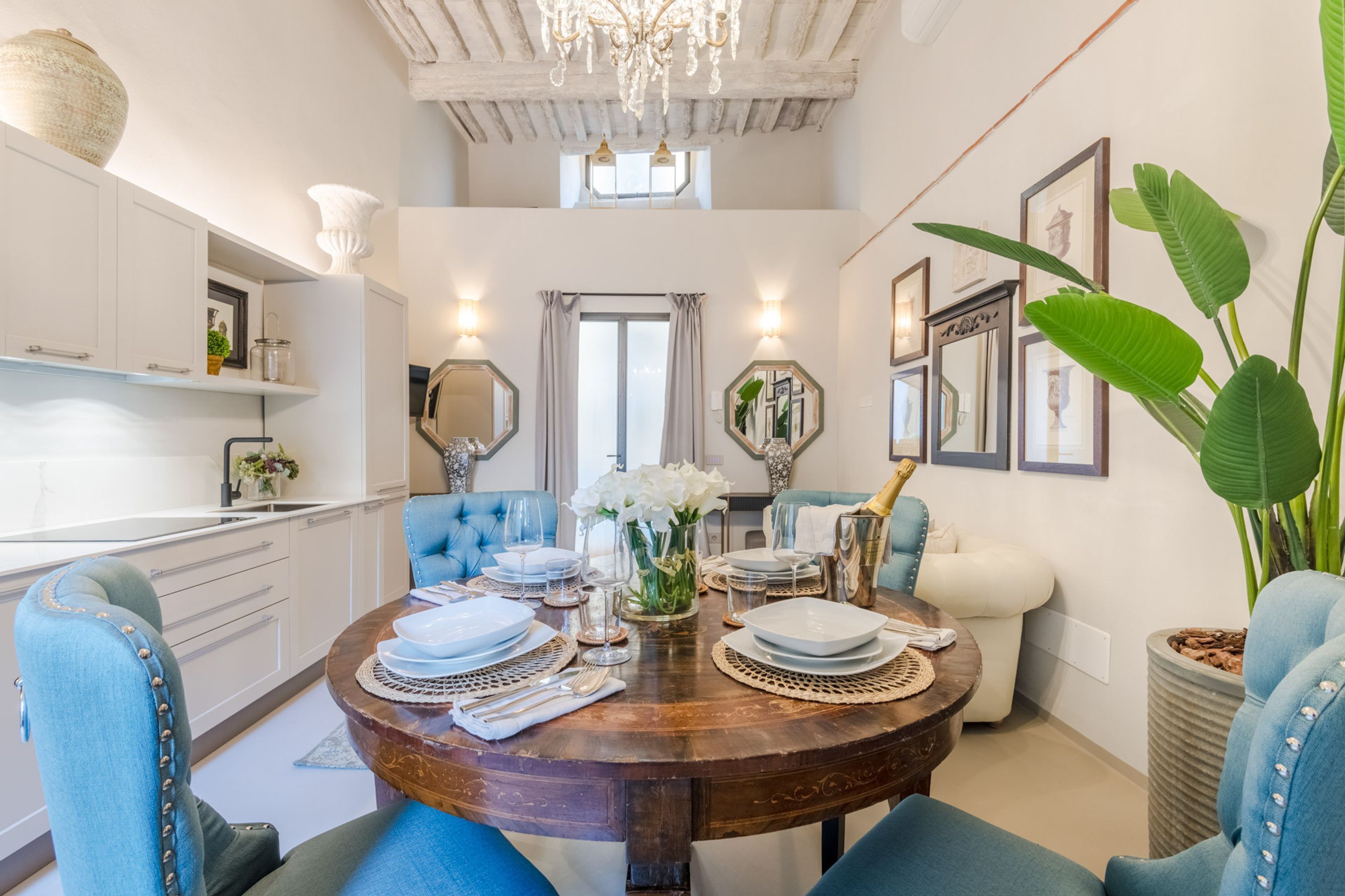 A dining area with a round wooden table set for four, surrounded by blue upholstered chairs.