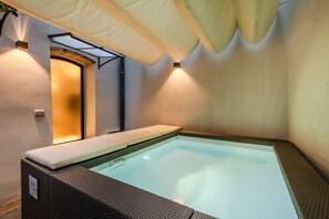 A spa area with a hot tub, a wall-mounted light, and a ceiling fan.