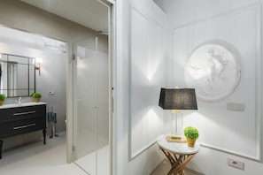 A modern bathroom with a glass shower, a black vanity, and a round mirror.
