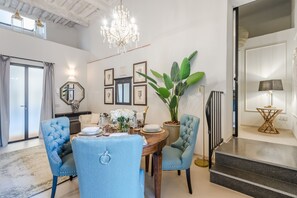 A dining area with a chandelier, a large potted plant, and a staircase leading to an upper level.