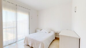 Ein schlicht eingerichtetes Schlafzimmer mit Bett, Nachttischen und Schreibtisch.