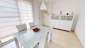 Eine moderne Küche mit Glastisch, weißen Schränken und einer Pendelleuchte.