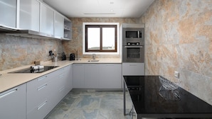 Una cocina moderna con armarios grises, encimera negra y salpicadero de piedra.