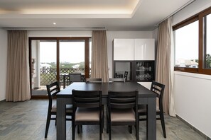 A dining area with a table and chairs, a kitchen area with cabinets, and a view through the glass door.