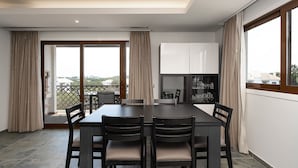 Un comedor con mesa y sillas, una zona de cocina con armarios, y vistas a través de la puerta de cristal.