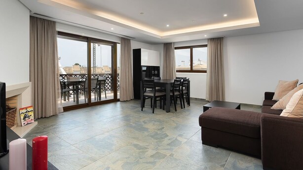Una sala moderna con sofá, comedor y balcón con vistas.