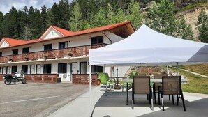 A two-story building with a red roof and balconies, a white tent, and outdoor seating. - Alpen Motel (Radium Hot Springs)