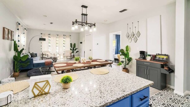 A modern kitchen with granite countertops, a dining area with a wooden table, and a kitchen island.