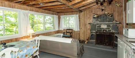 Ein rustikales Blockhaus im Inneren mit Essbereich, Kamin und Küche.