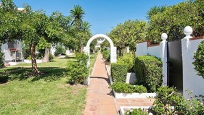 A pathway leading through a well-maintained garden with a white archway, surrounded by greenery and white walls. - Family Apartment with Pool by Costarentals - Ref 218 (Torremolinos)