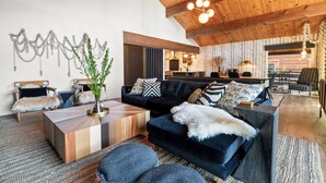 A spacious living area with a dark blue sofa, wooden coffee table, and a rustic ceiling with exposed beams.