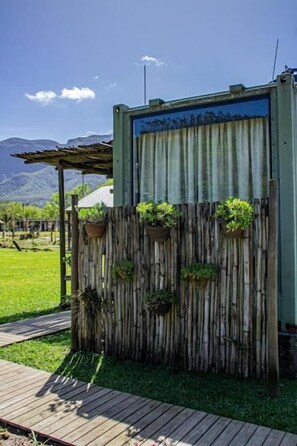 A rustic wooden fence with hanging planters, a wooden deck, and a mountain backdrop. - Éden Bed & Nature (Praia Grande)