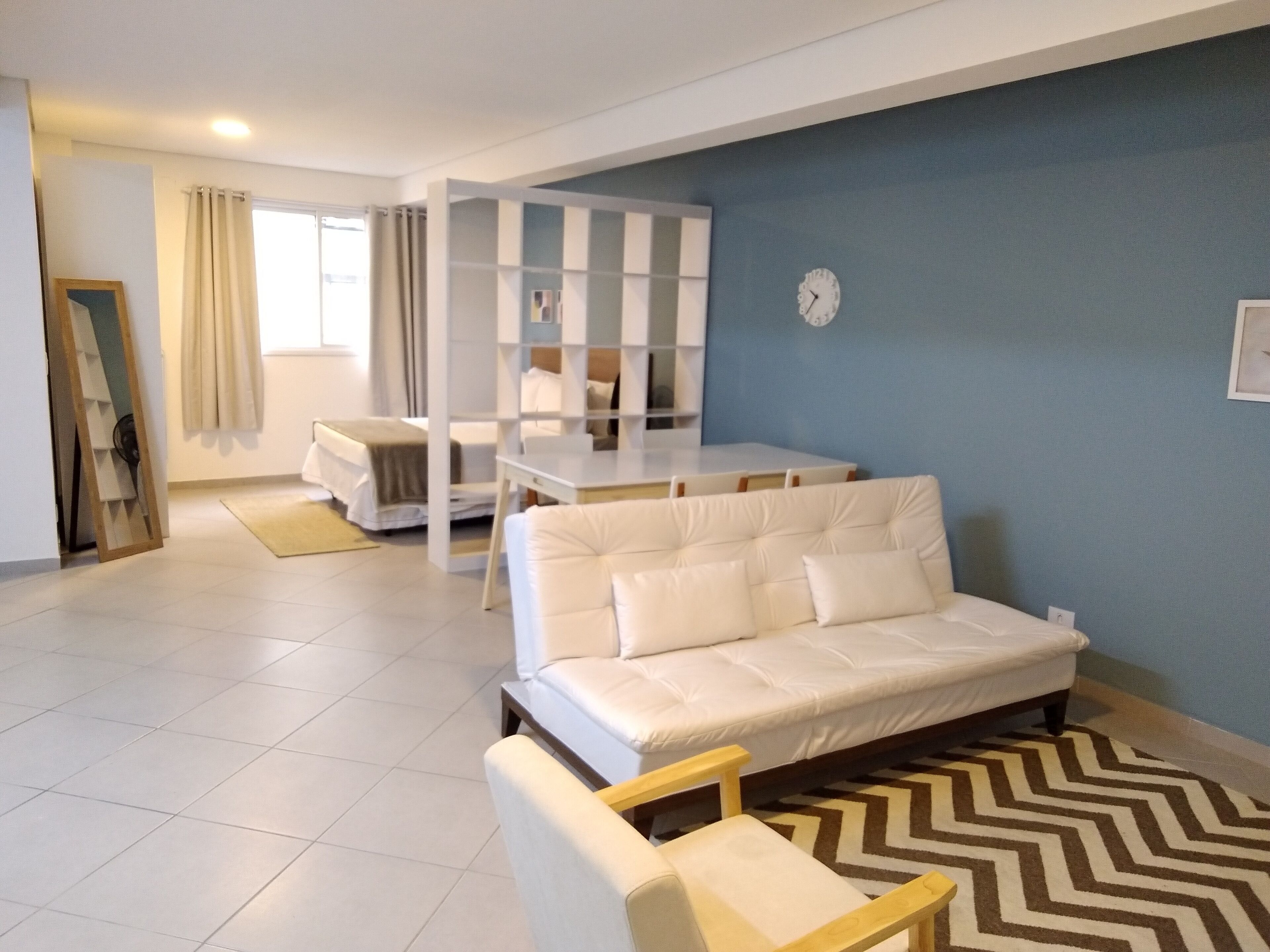 Een moderne woonkamer met een witte bank, een klein tafeltje en een blauwe accentmuur.