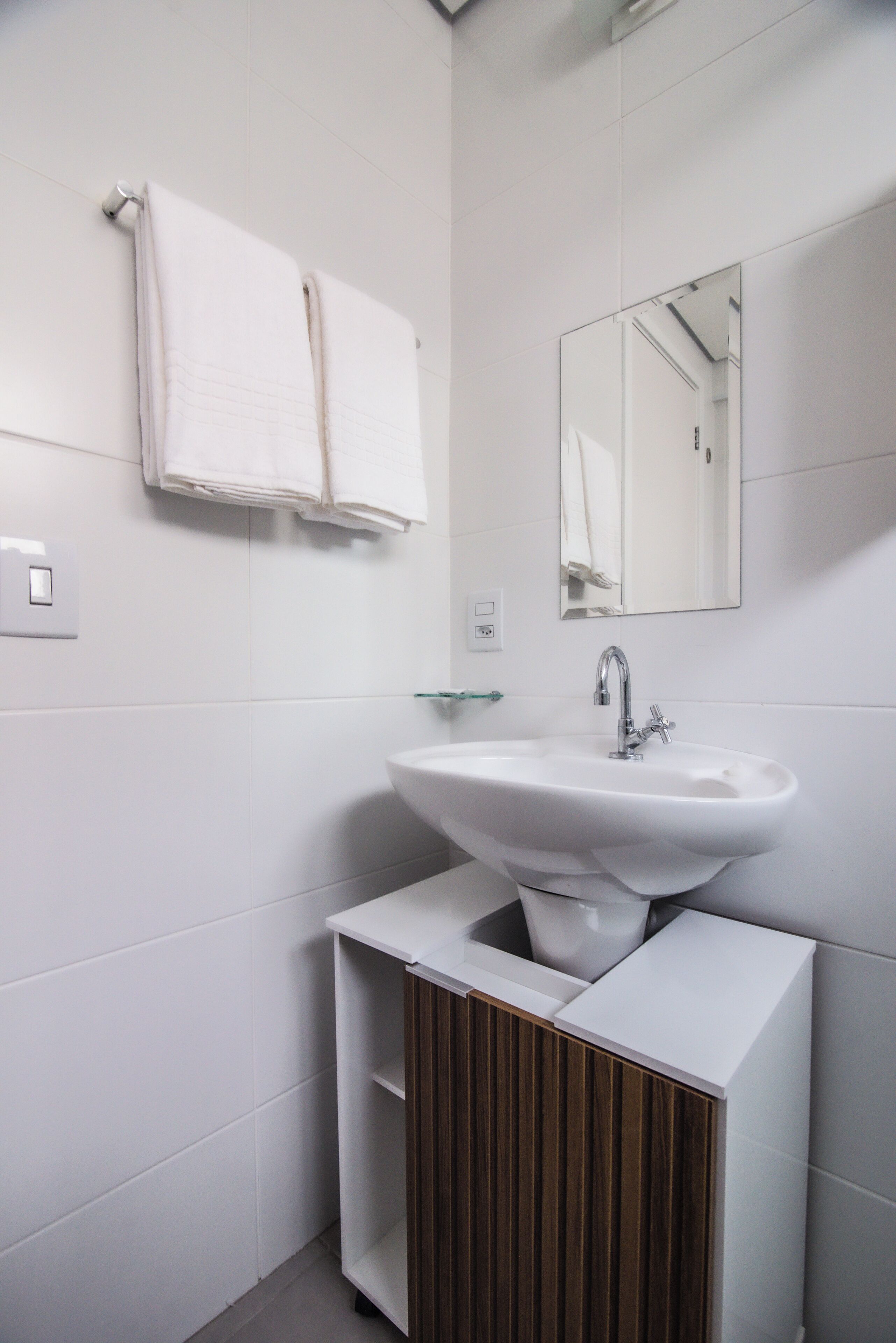 A modern bathroom with a white sink, a mirror, and two towels hanging on the wall.