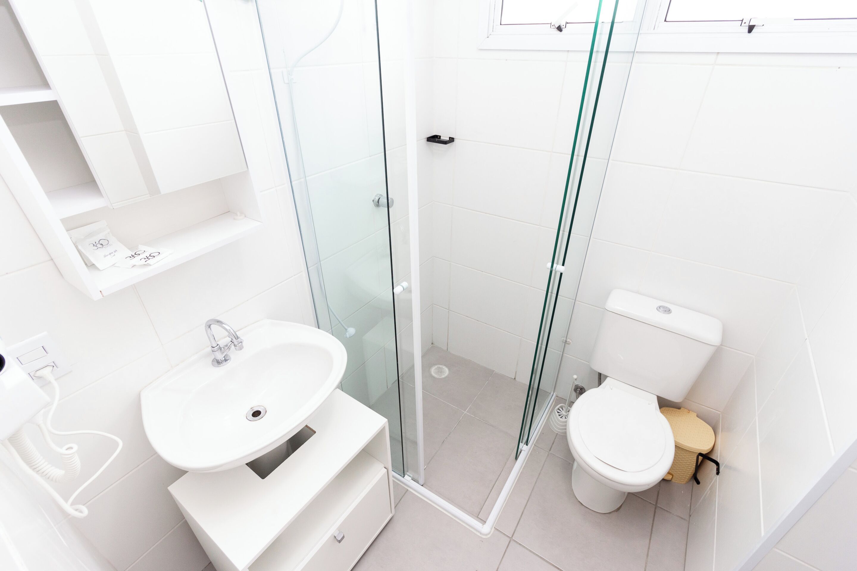 A modern bathroom with a glass-enclosed shower, a white sink, and a toilet.