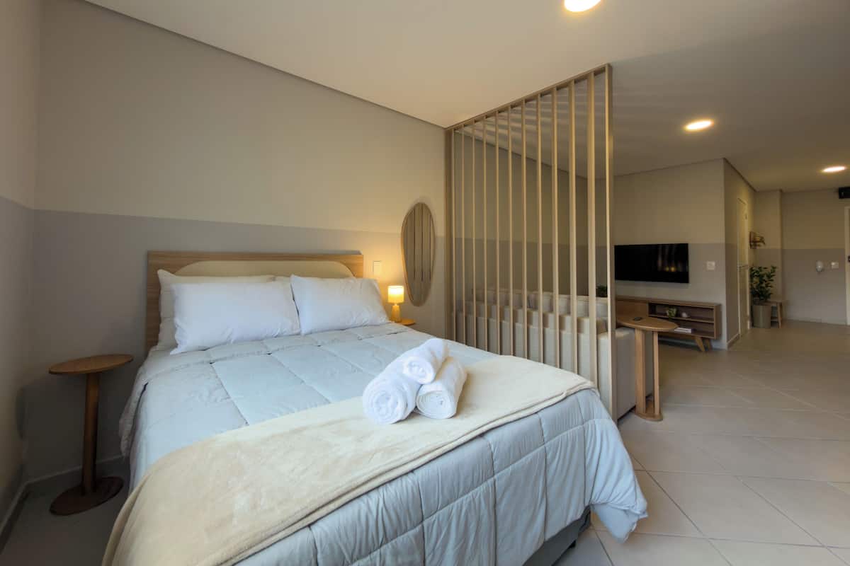 Ein modernes Hotelzimmer mit einem großen Bett, einem Fernseher, einem Schreibtisch und einer Sitzecke.