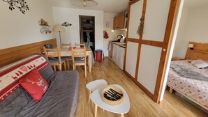 A compact room with a sofa, a dining table, a kitchen area, and a bed. - Cosy apt 4 ppl, near the ski runs (Chamrousse)