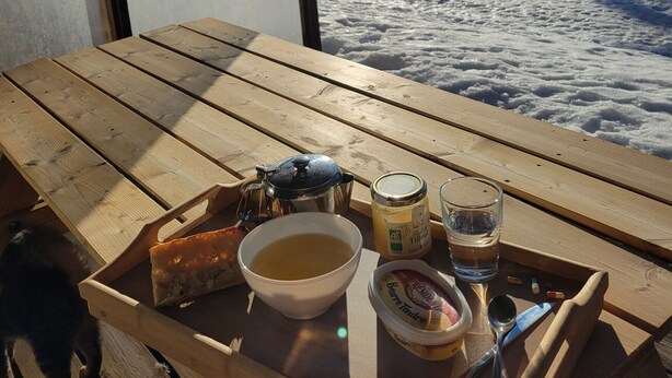 A wooden table with a tray containing a bowl of soup, a jar of jam, a glass of water, a spoon, and a knife. - Cosy apt 4 ppl, near the ski runs (Chamrousse)