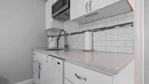 Une cuisine moderne avec des meubles blancs, un four à micro-ondes encastré et un lave-vaisselle.